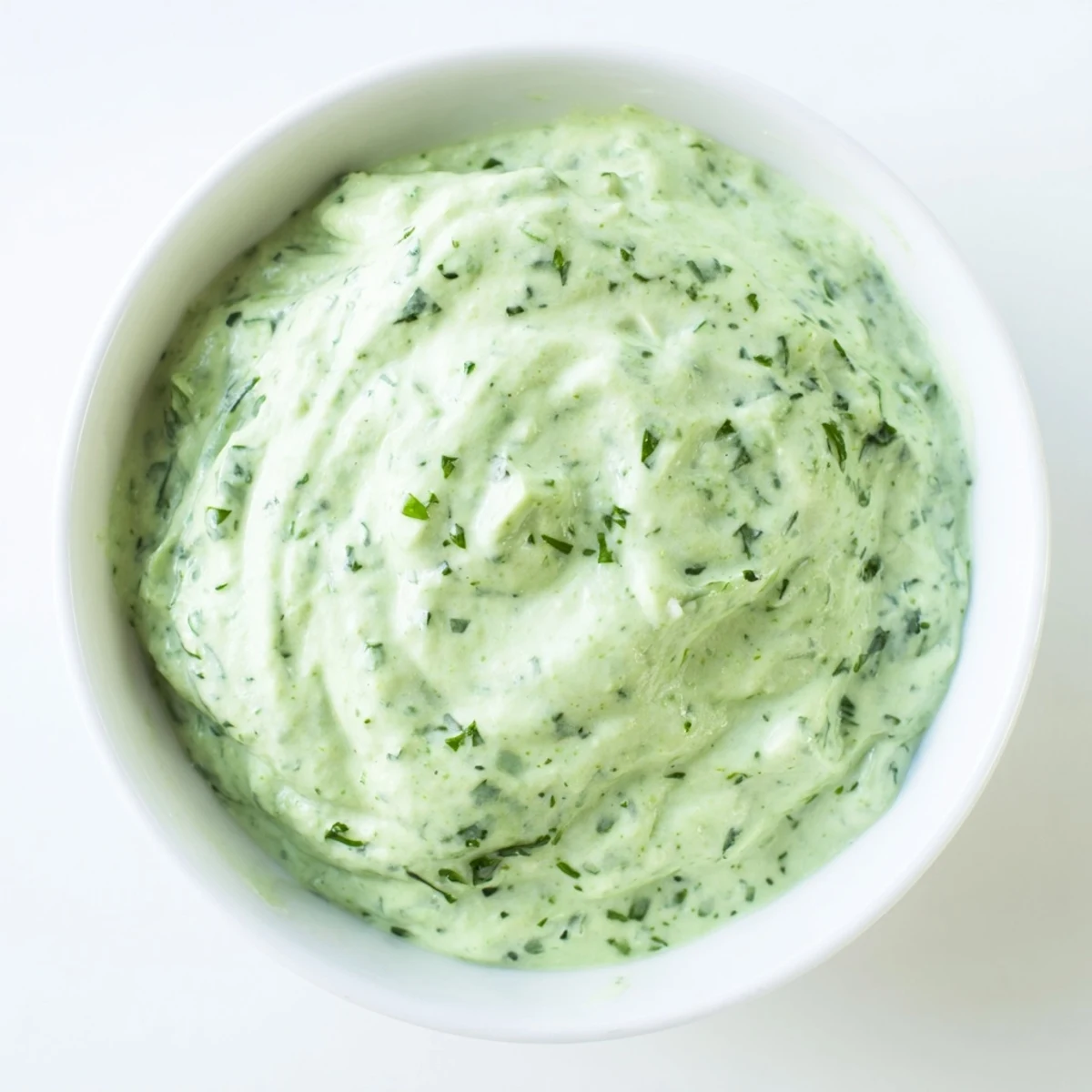 Vibrant Green Goddess Dressing being spooned from a blender, highlighting its rich, herby texture ready for drizzling or dipping.