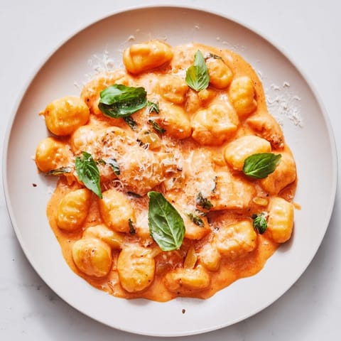 A flavorful skillet of creamy tomato gnocchi with fresh basil, ready to enjoy at home.