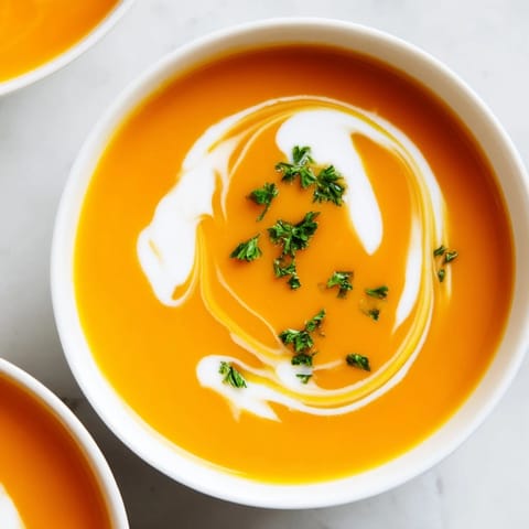 A spoonful of warm Carrot-Based Creamy Soup garnished with parsley, paired with crusty bread on the side.