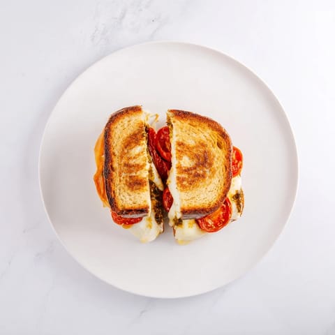 Golden roasted tomatoes and melted mozzarella on a crispy sourdough sandwich spread with basil pesto.  