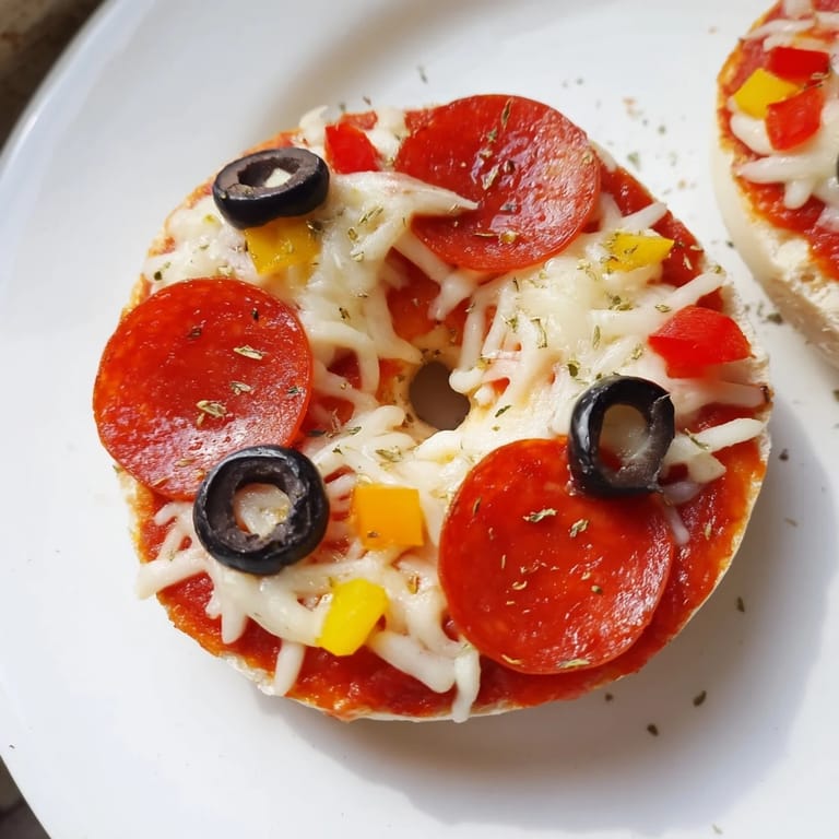 Close-up of air fryer mini bagel pizzas showcasing gooey mozzarella and savory pepperoni toppings.