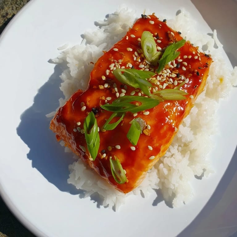 Gooey, caramelized Sticky Orange Salmon paired with rice, showing off a vibrant, flavorful sauce.