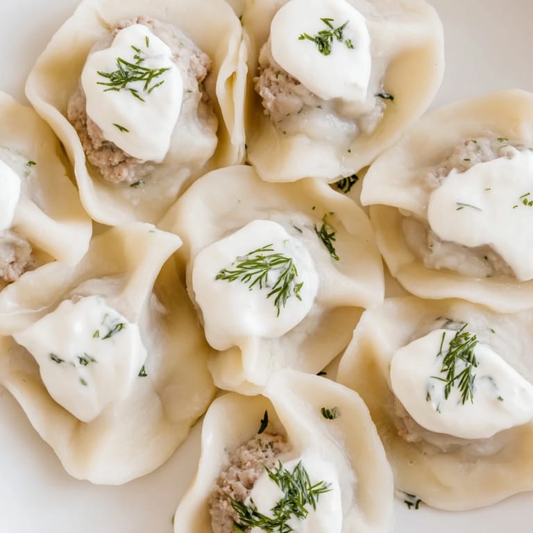 Golden-brown, freshly boiled Russian Pelmeni, a comforting main dish ready to serve, with a dill garnish.
