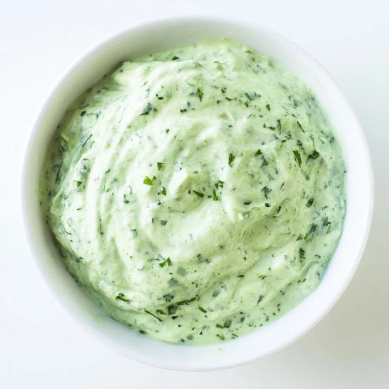 Vibrant Green Goddess Dressing being spooned from a blender, highlighting its rich, herby texture ready for drizzling or dipping.