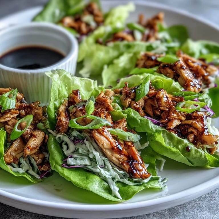 Potsticker-Inspired Chicken Lettuce Boats filled with savory chicken, topped with julienned carrots and sesame seeds on a crisp lettuce leaf.